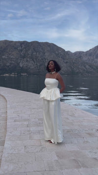 A woman wearing a cream luxury silk satin blouse paired with wide leg pants, turning around to show the 360 look of the outfit